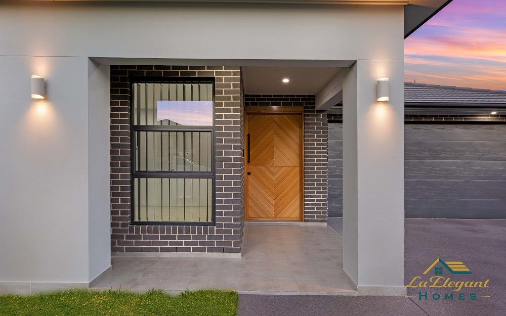 Recessed entry portico with a chevron timber front door on a home built by LA Elegant Homes
