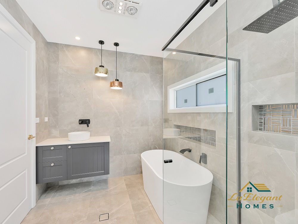 Ensuite with a freestanding bath, frameless walk-in shower, stone-look tiling and copper pendant lights